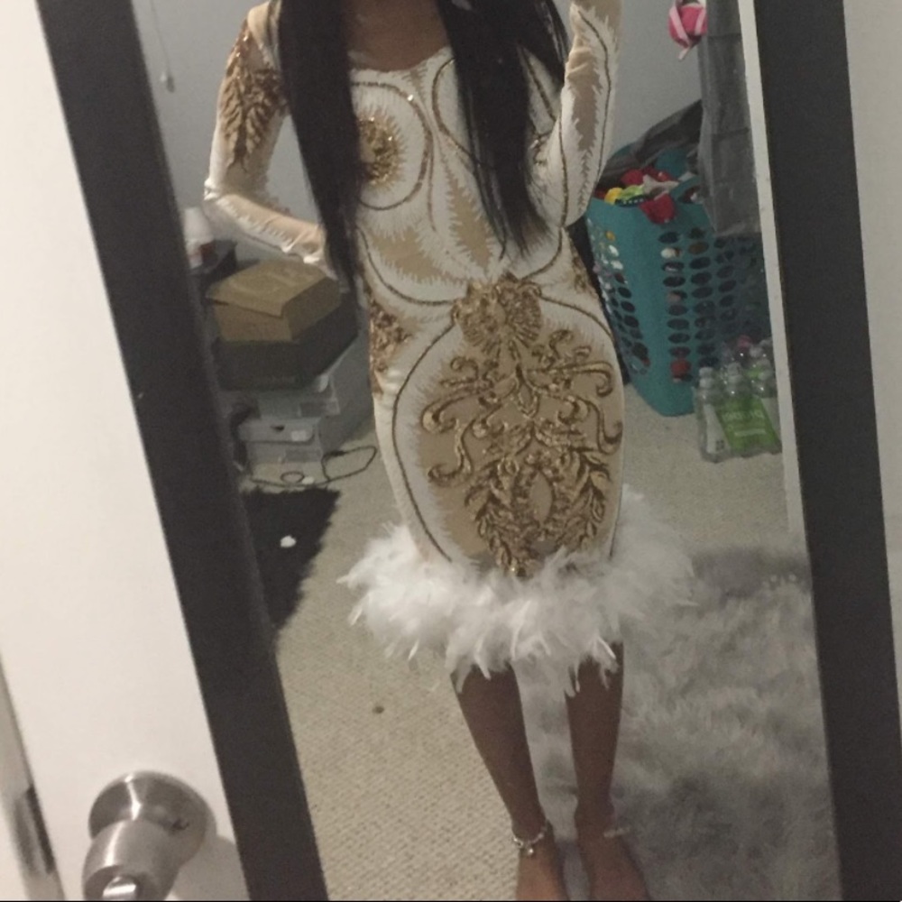long sleeve white dress with gold details and white feathers at the bottom
